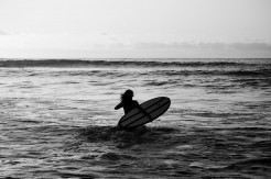 Surferin trägt ihr Surfboard durch die Brandung